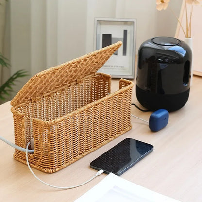 Handmade rattan wire management box for desk organization with open lid and charging phone.