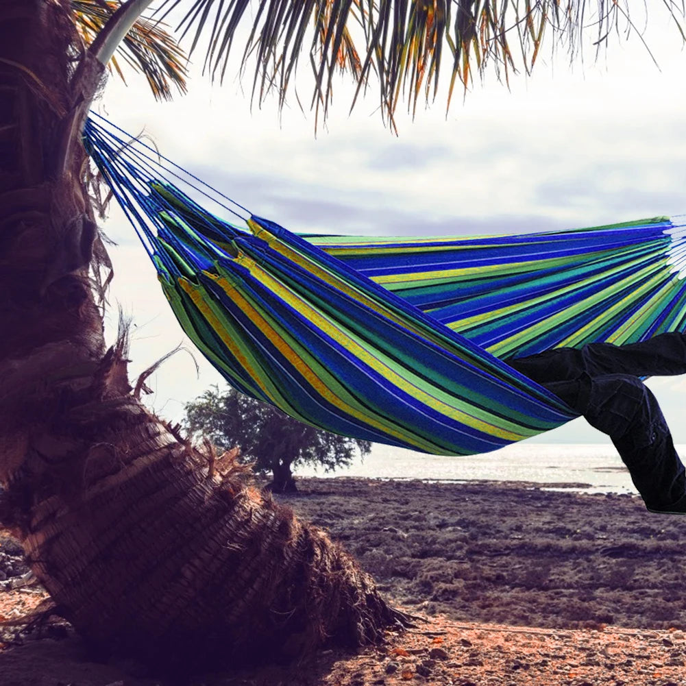 Double Hammock w/Stand, 2-People Hammock & Stand set between palm trees by the beach, colorful blue and green stripes.