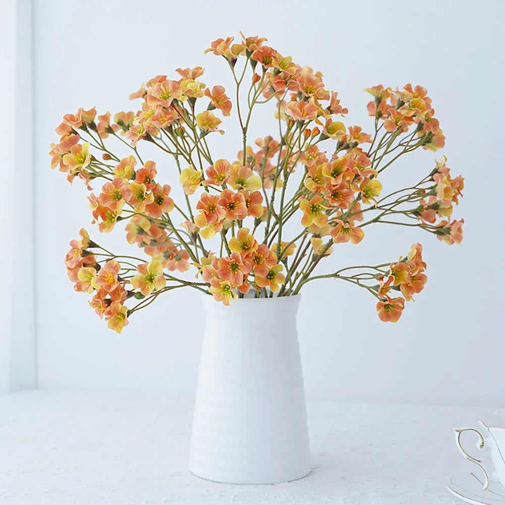 Artificial cornflower decorative flowers in a white vase with orange and yellow blooms.
